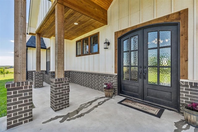 view of exterior entry featuring board and batten siding, french doors, and covered porch
