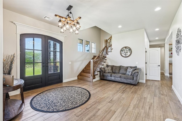 entrance foyer featuring french doors, light wood finished floors, visible vents, stairs, and arched walkways