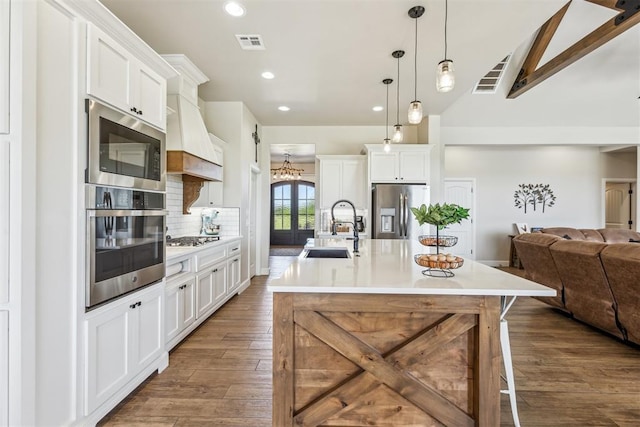 kitchen with visible vents, a sink, open floor plan, backsplash, and appliances with stainless steel finishes