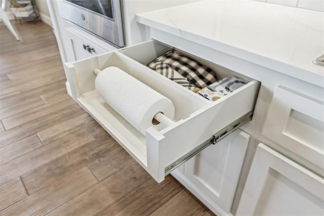 details with white cabinetry and wood finished floors