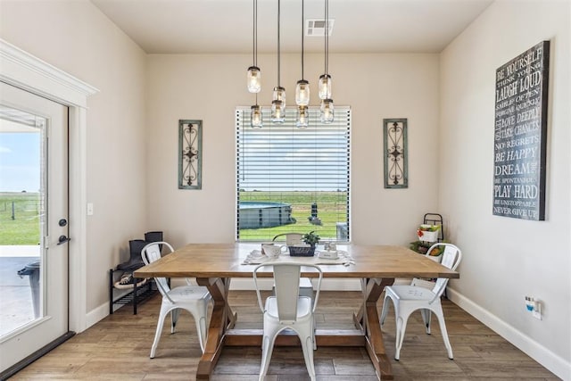 dining space featuring light wood-style floors, visible vents, baseboards, and a notable chandelier