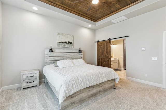 bedroom featuring wood ceiling, baseboards, a barn door, and a raised ceiling