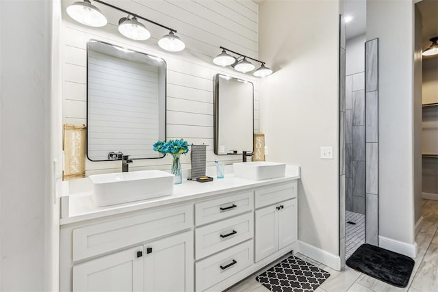 full bathroom featuring a sink, double vanity, wooden walls, and a stall shower