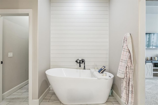 bathroom with a freestanding bath and baseboards