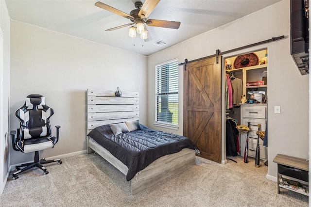 bedroom with a barn door, visible vents, carpet flooring, a ceiling fan, and baseboards