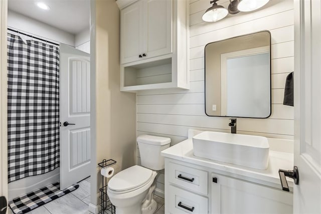 bathroom featuring vanity, toilet, tile patterned flooring, and wood walls