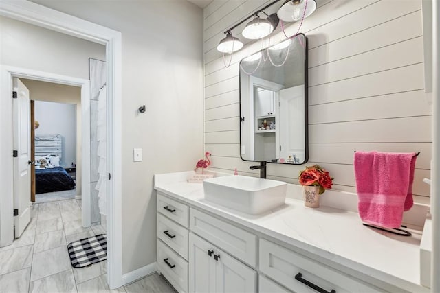 ensuite bathroom with vanity, wooden walls, connected bathroom, and marble finish floor