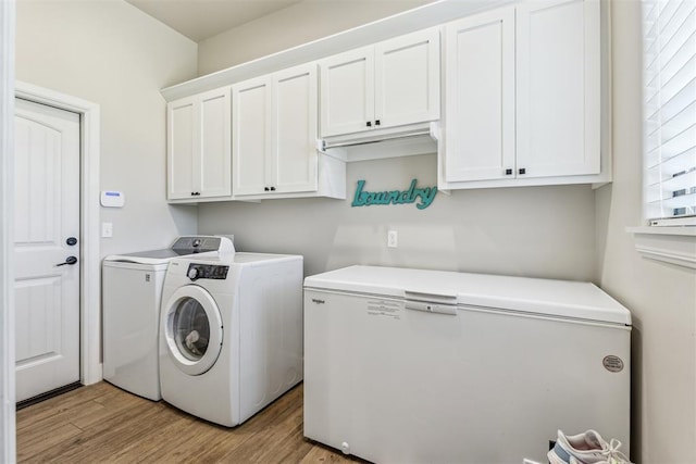 clothes washing area with cabinet space, washer and clothes dryer, and light wood-style flooring