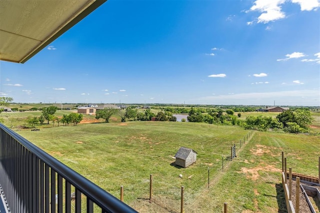 view of yard featuring a rural view, an outbuilding, a shed, and fence