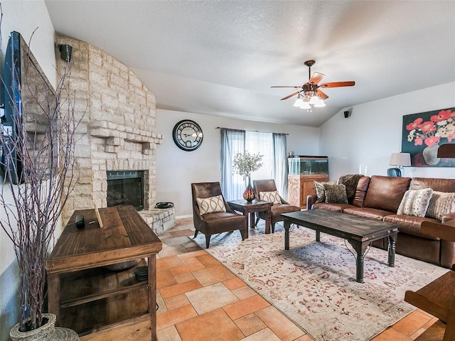 living area featuring a stone fireplace, stone finish floor, a ceiling fan, baseboards, and lofted ceiling