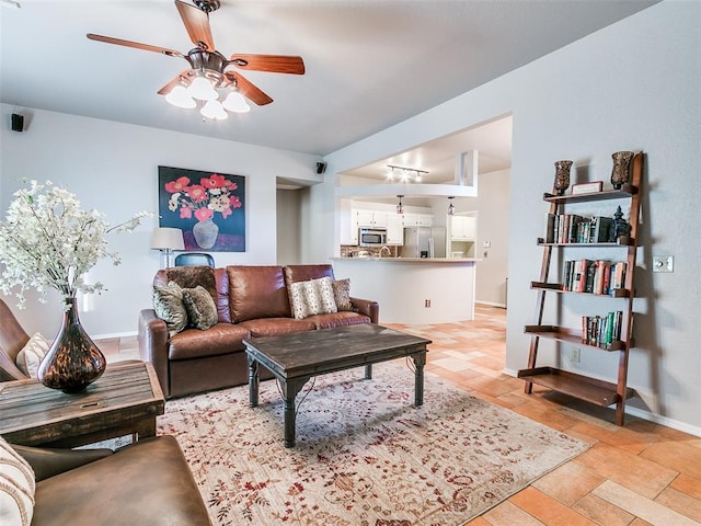 living area with a ceiling fan, baseboards, and stone finish floor