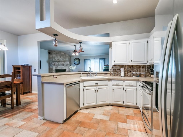 kitchen featuring a sink, a peninsula, light countertops, a ceiling fan, and appliances with stainless steel finishes