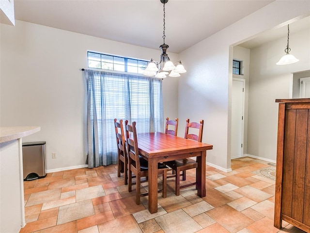 dining area with baseboards, an inviting chandelier, and stone tile flooring