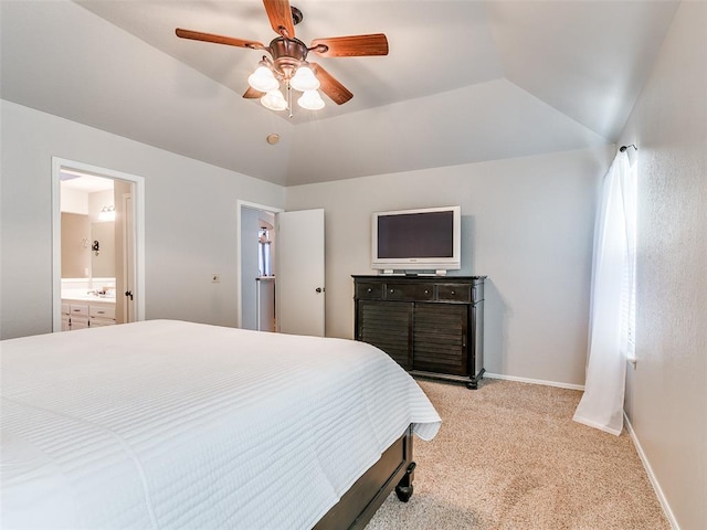bedroom featuring baseboards, light colored carpet, a ceiling fan, ensuite bath, and vaulted ceiling