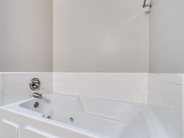 full bathroom with a textured wall and a tub with jets