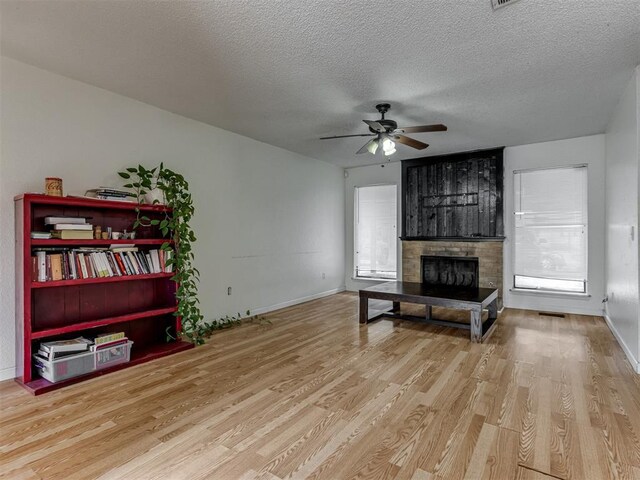 3800 Southwind Ct, Oklahoma City, OK 73179 - unfurnished living room featuring a fireplace, wood finished floors, a textured ceiling, and ceiling fan