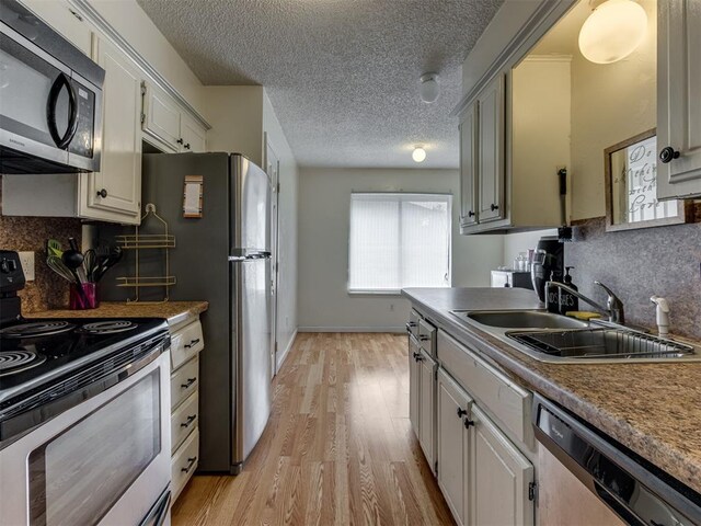 3800 Southwind Ct, Oklahoma City, OK 73179 - kitchen with appliances with stainless steel finishes, light wood-style floors, decorative backsplash, and a textured ceiling