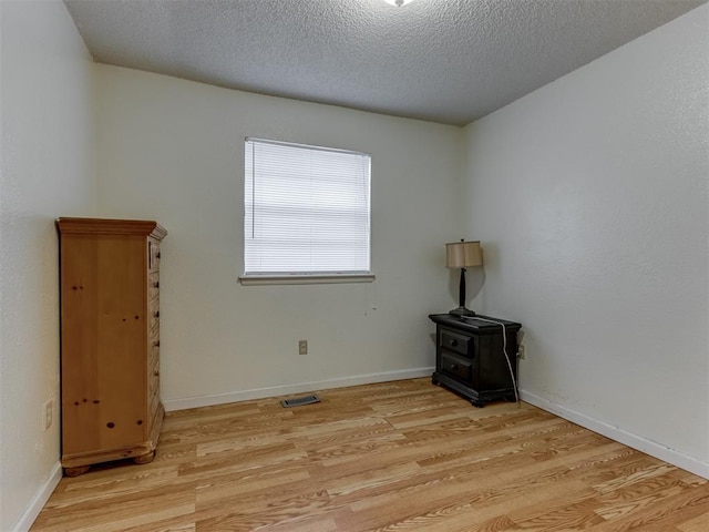 3800 Southwind Ct, Oklahoma City, OK 73179 - empty room with a wood stove, light wood finished floors, and a textured ceiling