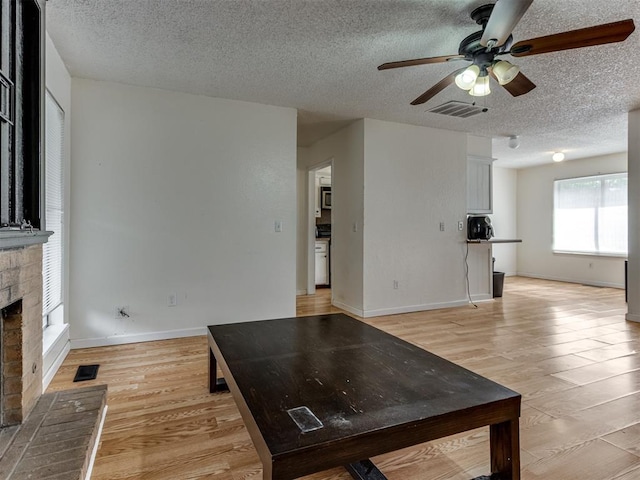 3800 Southwind Ct, Oklahoma City, OK 73179 - unfurnished living room with ceiling fan, a textured ceiling, light wood-style flooring, and a fireplace