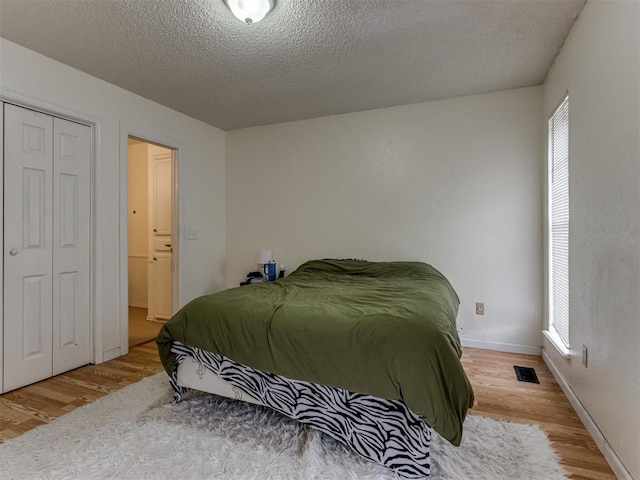 3800 Southwind Ct, Oklahoma City, OK 73179 - bedroom featuring multiple windows, a closet, wood finished floors, and a textured ceiling