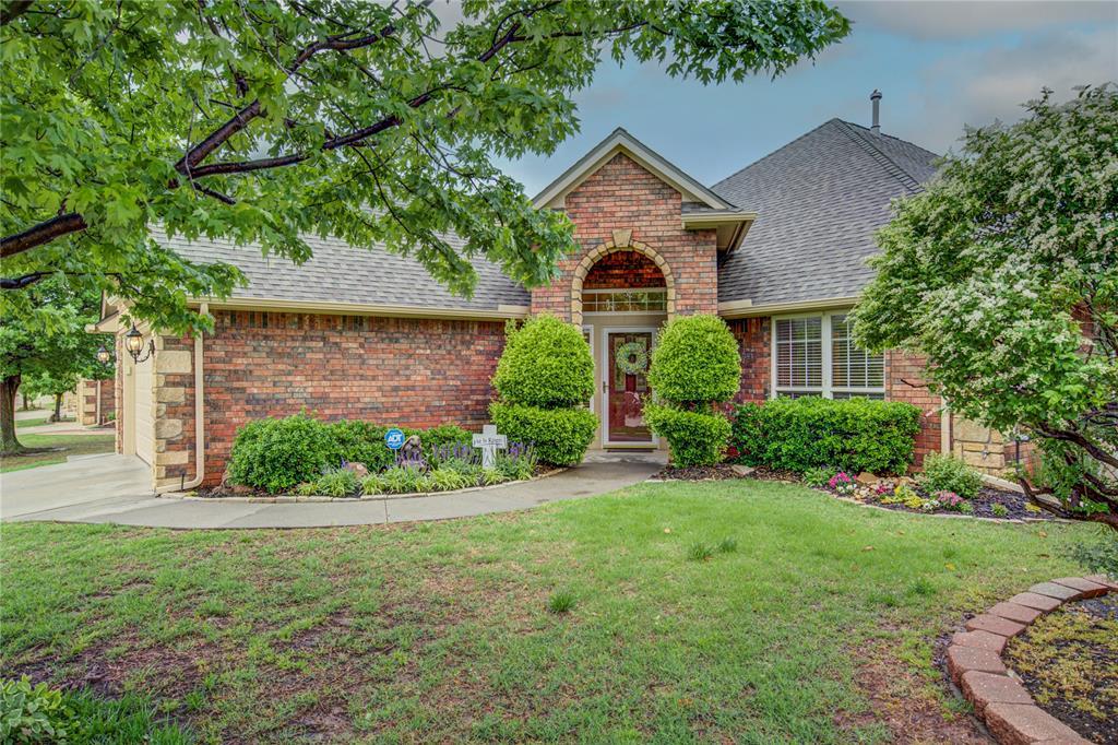 traditional-style house featuring roof with shingles, a front yard, and brick siding