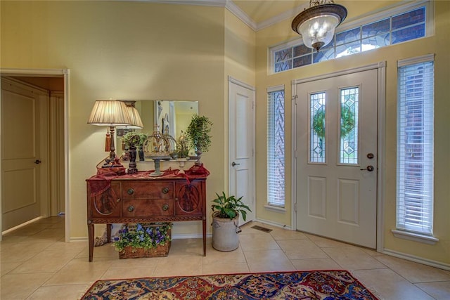 foyer entrance with crown molding, tile patterned floors, baseboards, and a high ceiling