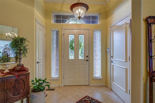 entryway featuring an inviting chandelier, ornamental molding, baseboards, and light tile patterned flooring