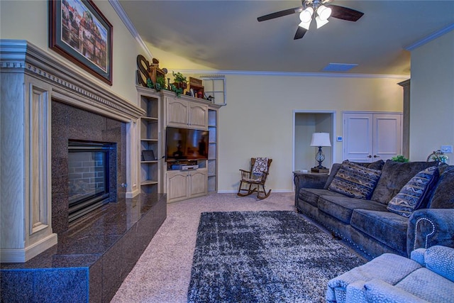 carpeted living area with baseboards, ornamental molding, a fireplace, and ceiling fan