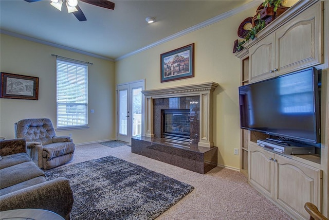 living room featuring crown molding, baseboards, ceiling fan, carpet, and a premium fireplace
