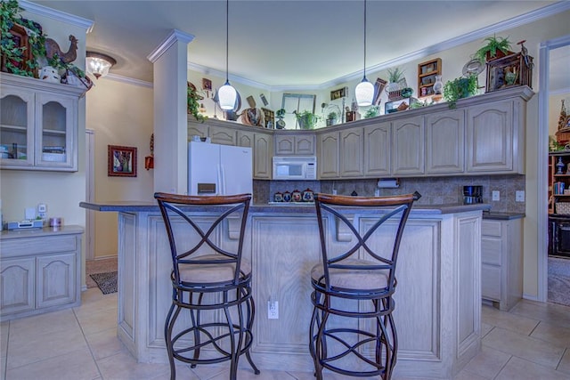 kitchen with white appliances, backsplash, crown molding, and a breakfast bar area