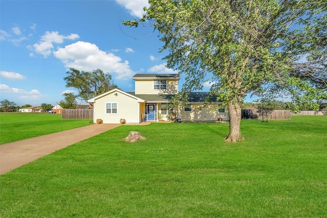 traditional-style house featuring a front yard, driveway, solar panels, and fence