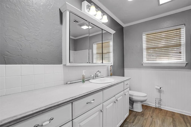 bathroom featuring tasteful backsplash, a wainscoted wall, toilet, ornamental molding, and wood finished floors