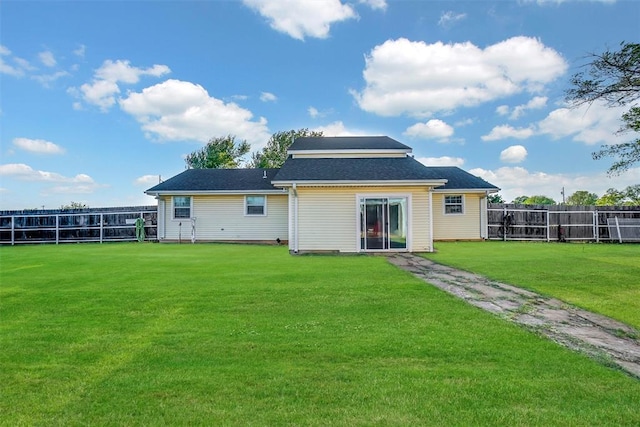 rear view of property featuring a lawn and fence