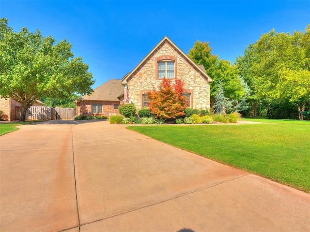 view of front of house featuring fence, a front lawn, and stone siding