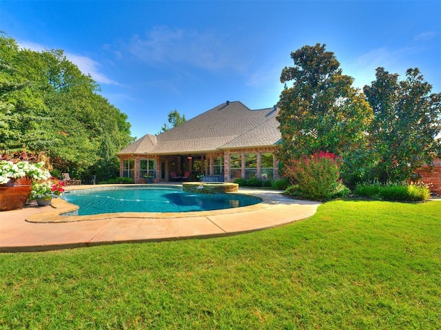 view of swimming pool featuring a patio, a yard, and a pool with connected hot tub