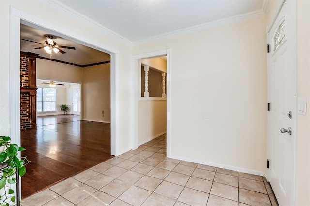 empty room with light tile patterned floors, ceiling fan, ornamental molding, and baseboards