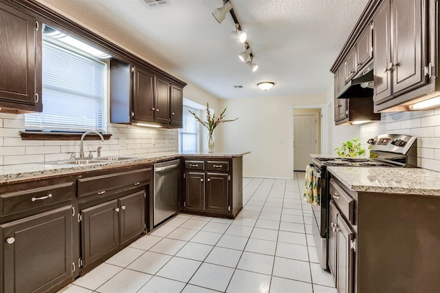 kitchen with under cabinet range hood, appliances with stainless steel finishes, dark brown cabinets, a sink, and a peninsula