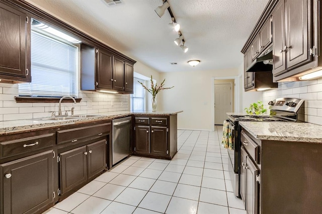 kitchen featuring a sink, appliances with stainless steel finishes, dark brown cabinets, under cabinet range hood, and backsplash