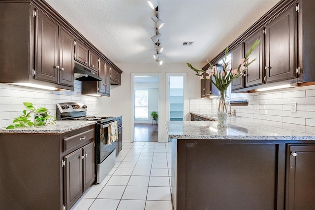 kitchen featuring range with electric stovetop, light tile patterned floors, dark brown cabinets, and under cabinet range hood