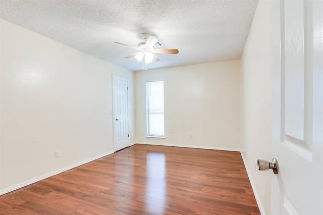 empty room featuring baseboards, wood finished floors, a ceiling fan, and a textured ceiling