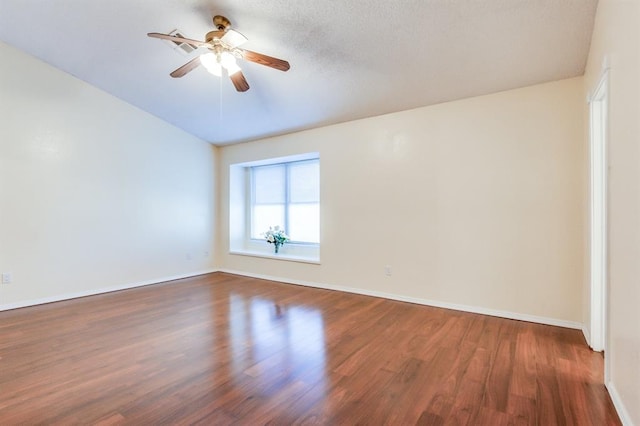 unfurnished room with dark wood-type flooring, a ceiling fan, and baseboards