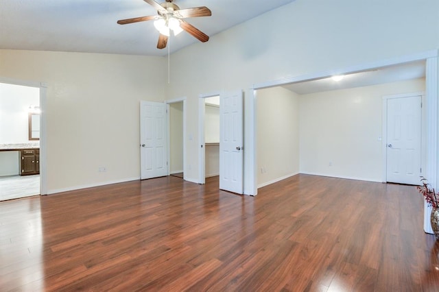 unfurnished bedroom featuring a spacious closet, dark wood-style floors, and baseboards