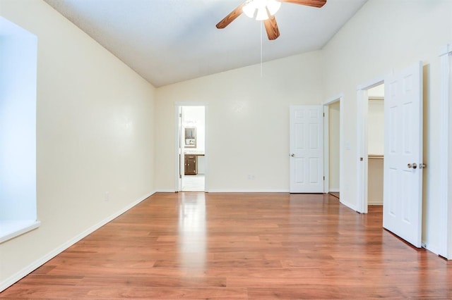 interior space with ceiling fan, wood finished floors, lofted ceiling, and baseboards