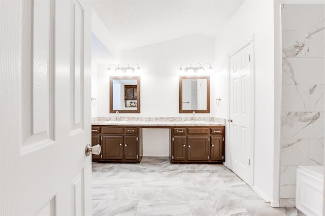full bathroom with vaulted ceiling, double vanity, marble finish floor, and a sink