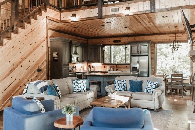 living area with visible vents, wood walls, wooden ceiling, a notable chandelier, and stairs