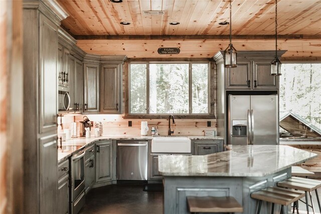 kitchen featuring hanging light fixtures, light stone counters, a sink, stainless steel appliances, and wood ceiling