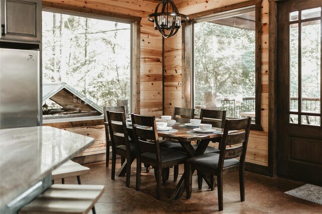 dining space featuring wood walls, a chandelier, and plenty of natural light
