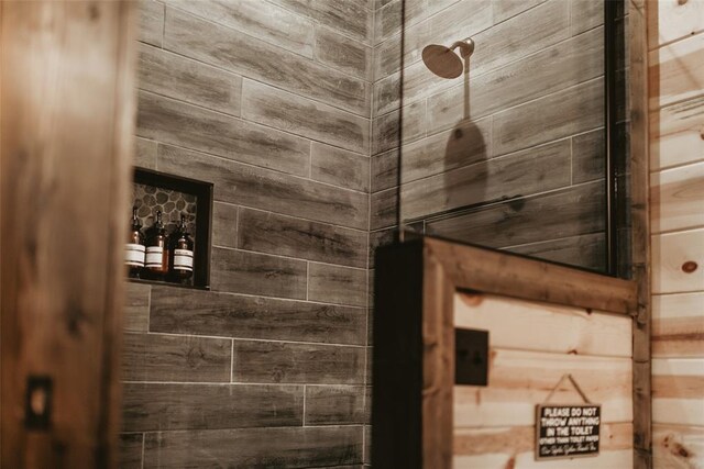bathroom with wooden walls and tiled shower