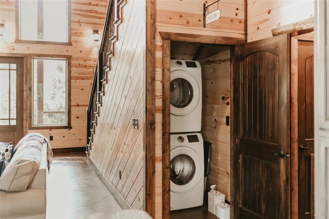 laundry area featuring laundry area, stacked washer / drying machine, and wooden walls