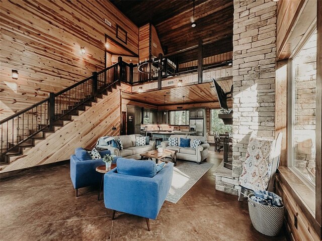 living area featuring wood ceiling, wood walls, stairs, and a towering ceiling
